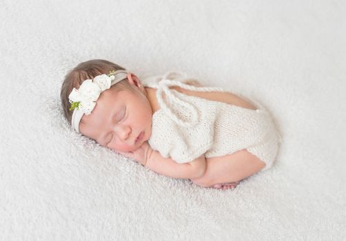Cute infant sleeping wearing wonderful white warm suit with a cut on the back