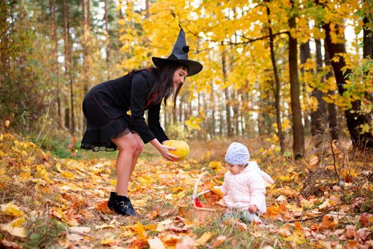 black witch woman with little toddler bunny in the autumn forest. halloween celebration, costume party.