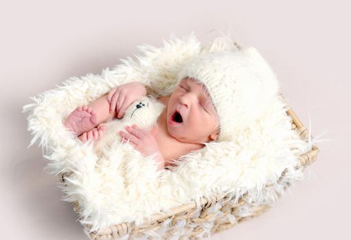 Sleeping newborn baby yawning. Baby sleeping in the small box covered with white soft blanket