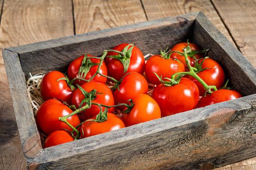 Red tomatoes in wooden market box. Wooden background. Top view.