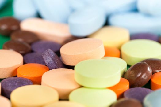 A large number of multi-colored tablets of different shapes and purposes with different medical properties lying together in a heap