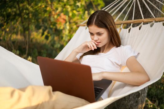woman with laptop lies in hammock freelance travel. High quality photo