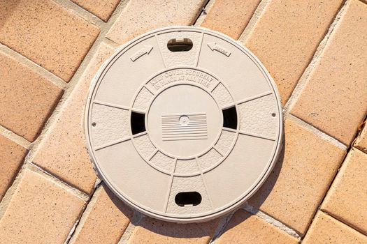 A swimming pool leaf filter cover inserted in paving stones
