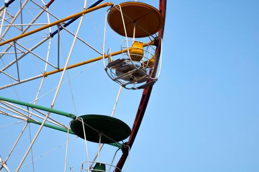 Close-up of a multi-colored Ferris wheel in an amusement park against a background of blue sky