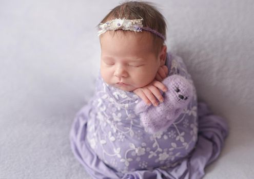 Cute sleeping newborn baby girl in violet