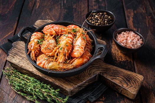 Cooking Greenland Shrimps Prawns in a pan with thyme and rosemary. Dark wooden background. Top view.