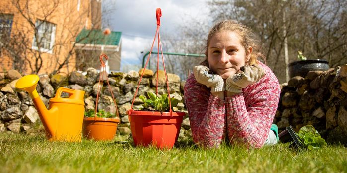 pfemale portrait of happy farmer woman in household gloves smiling with flower in a pot sunny day,