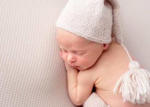 Cute baby in white knitted hat and pants sweetly sleeping