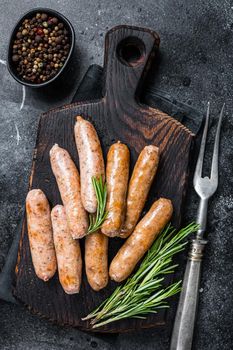 Fried Bratwurst or Hot Dogs sausages on a wooden board. Black background. Top View.