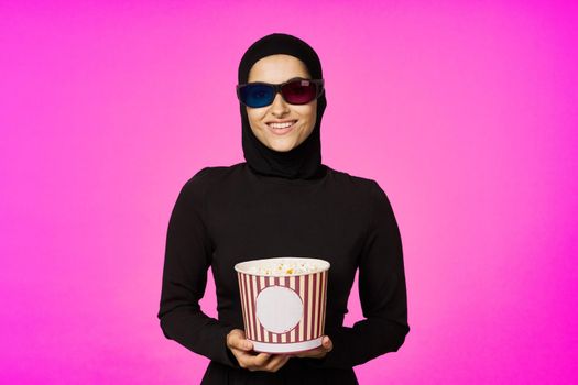 arab woman in 3D glasses popcorn entertainment movies purple background. High quality photo