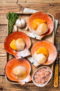 Scallops seafood on a wooden board with salt and herbs. wooden background. Top view.