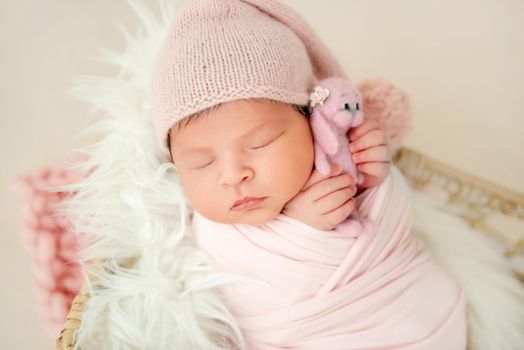 newborn baby girl sleeping sweetly with a small toy