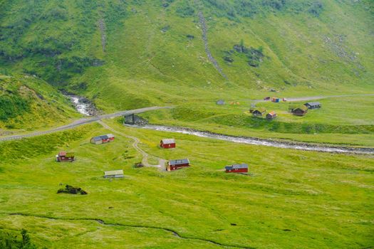 Beautiful landscape and scenery view of Norway, green scenery hills and mountain in a cloudy day. green scenery of hills and mountain partially covered with fog. Farm and cottages on a glacier river.