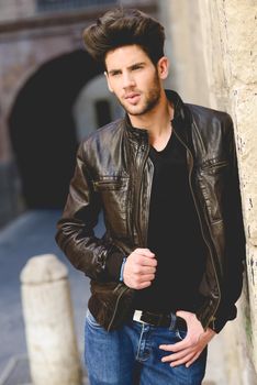Portrait of a young handsome man, model of fashion, with modern hairstyle in urban background wearing leather jacket