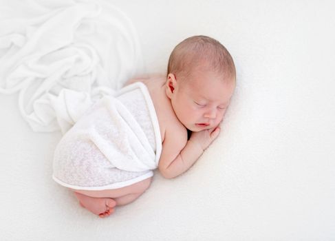 Newborn beatiful cute baby sleeping in white blanket on white bed background