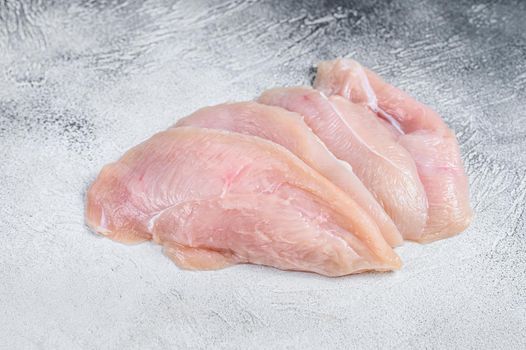 Raw sliced chicken breast fillet steaks. White background. Top view.