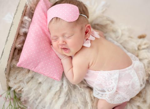 Funny newborn sleeping in tiny bed