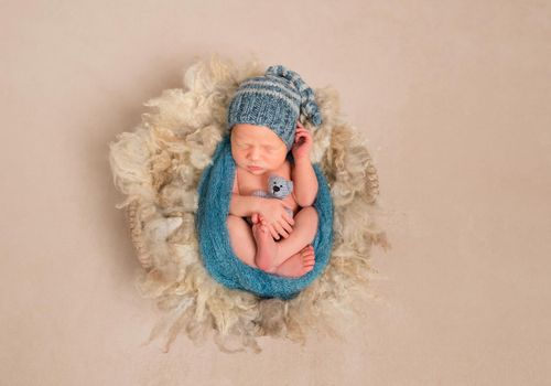 Little kid wrapped in a blue scarf in a hat resting, topview