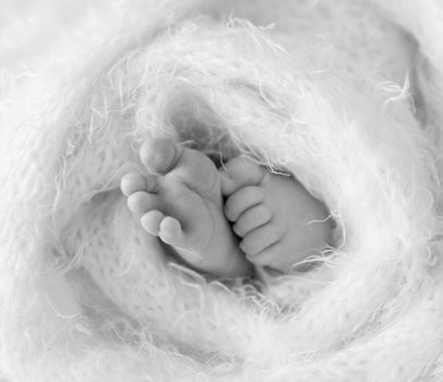 Little feet and toes of an infant sleeping tighly covered with soft warm blanket