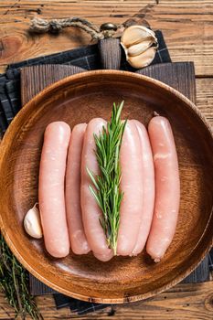 Poultry raw sausages in a wooden palte with herbs. wooden background. Top view.