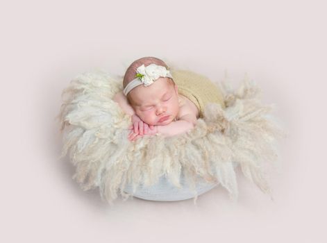 Adorable girl sleeping on huge soft fury pillow, wearing cute little headband