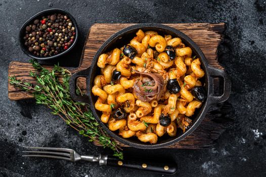 Pasta Cellentani Puttanesca seafood pasta in a pan. Black background. Top view.