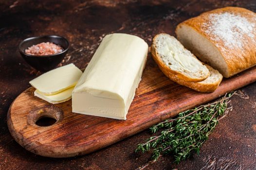 Butter spread and foodstuff toasts on a wooden cutting board. Dark background. Top view.