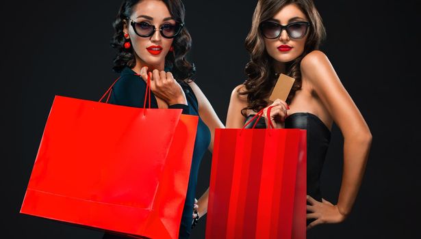 Beautiful young woman make shopping in black friday holiday. Girl with black bag on dark background.