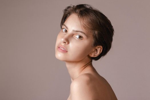 Beautiful young woman with absolutely no makeup on a neutral gray background