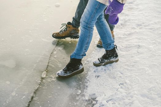 Trying the danger of the foot, testing the thin ice near the shore. A pair of lovers walk with a walk along a frozen lake to press foot on the ice.