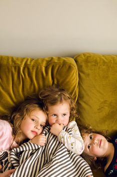 Cute little girls chilling on soft couch in living room together at home