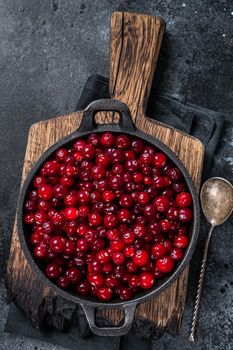 Red fresh Cranberry berry in a pan. Black background. Top view.