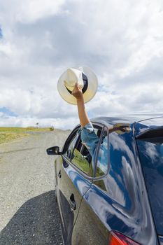 female hand holding hat out car window