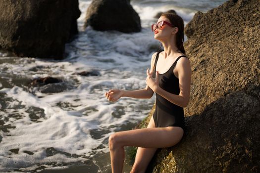 woman in black swimsuit rocks posing oceans. High quality photo