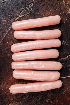 Raw chicken and turkey meat sausages on butcher table. Dark background. Top view.