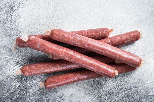 Raw butchers sausages in skins with herbs on kitchen table. White background. Top view.