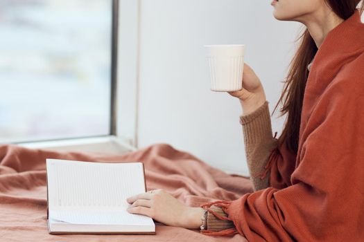 woman near the window with a plaid reading a book rest. High quality photo