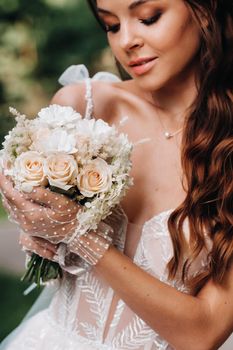 portrait of an elegant bride in a white dress with a bouquet in nature in a nature Park.Model in a wedding dress and gloves and with a bouquet .Belarus.