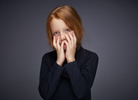 red-haired girl with freckles on her face in a black sweater posing. High quality photo