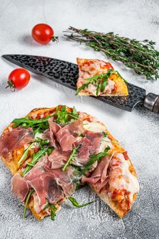 Italian Pizza with parma ham, arugula and cheeseon a kitchen table. White background. Top view.