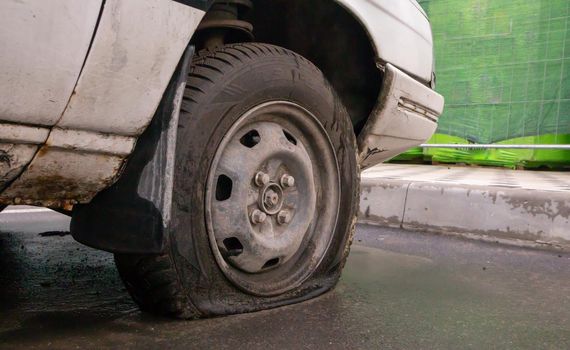 Abandoned old broken car with flat wheels. A tire with a flat tire. The concept of accident, breakdown, repair, insurance. A flat tire on a car wheel. Ukraine, Kiev - August 19, 2021