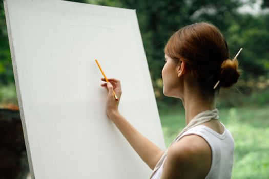 an artist in nature draws on an easel with a pencil. High quality photo