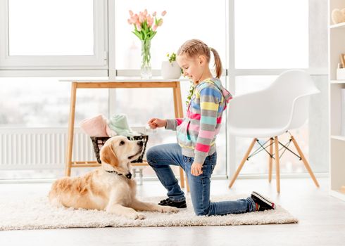 Cute little girl training young dog at home