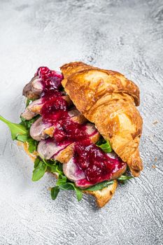 Duck breast Croissant sandwich with steak slices, arugula and sauce. White background. Top View.