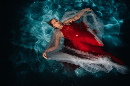 A girl in a red dress is floating on the water.A journey on the water of a single woman.