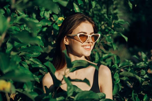 smiling woman wearing sunglasses green leaves nature fashion. High quality photo