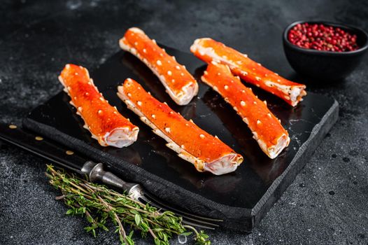 Crab legs Phalanx on a marble board with thyme. Black background. Top view.