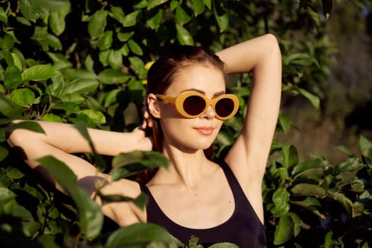 pretty woman in black swimsuit sunglasses green leaves nature. High quality photo