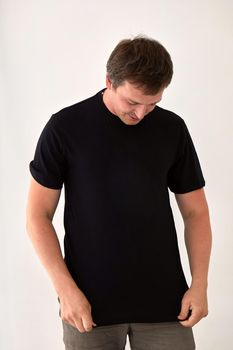 Young male model wearing basic black t shirt with space for print standing against white background