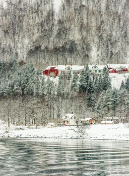 wooden houses on the banks of the Norwegian fjord, beautiful mountain landscape in winter